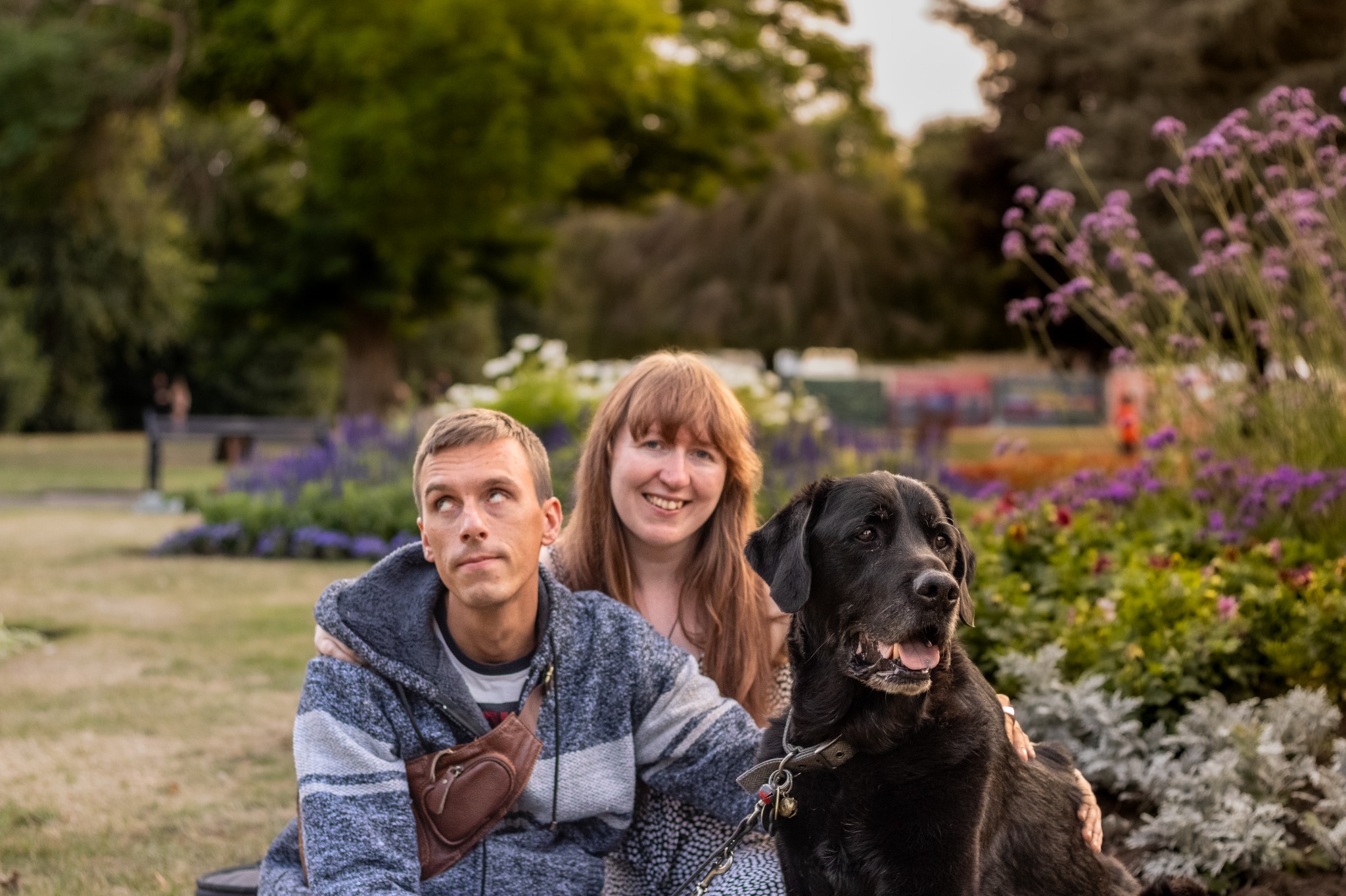 A couple sitting with their dog in a flower garden